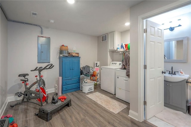 3118 Kimball Ave, Kansas City, KS 66104 - laundry room with electric panel, washing machine and clothes dryer, light wood-type flooring, cabinet space, and baseboards