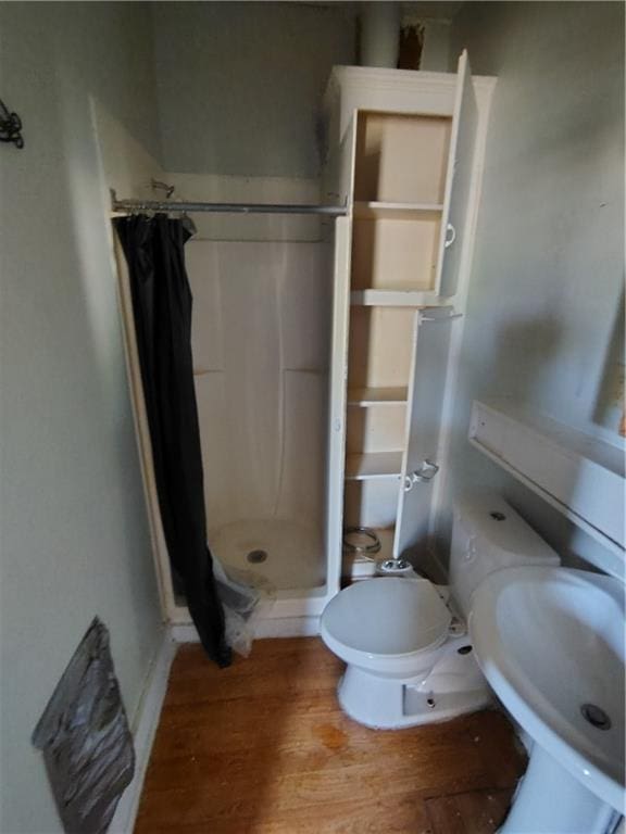full bath with a stall shower, wood finished floors, and toilet