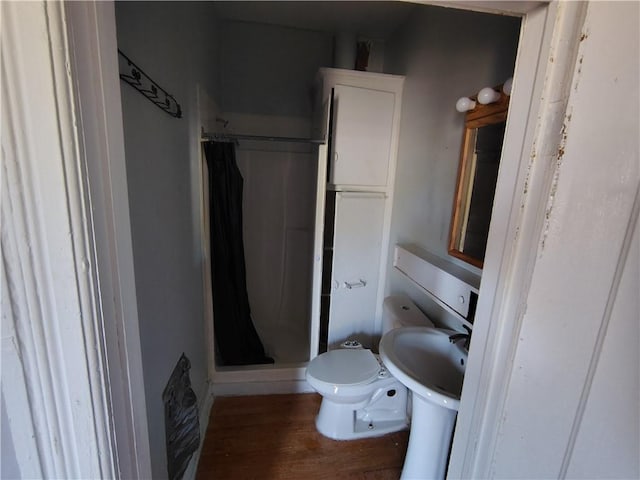 full bath with a shower stall, wood finished floors, and toilet