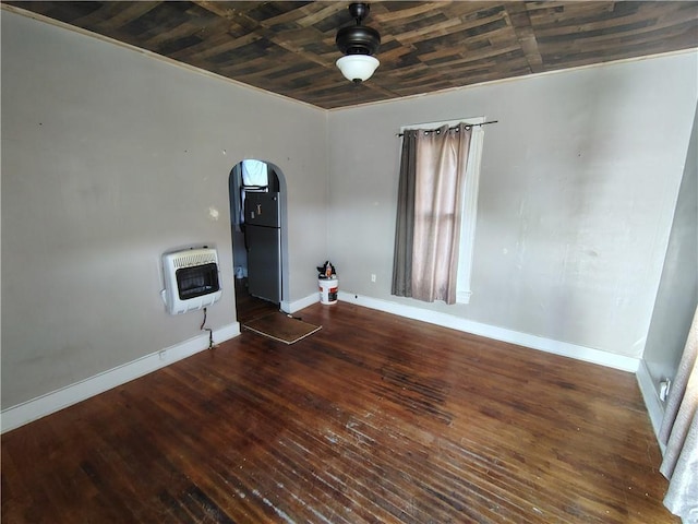 unfurnished room with heating unit, arched walkways, baseboards, and wood finished floors