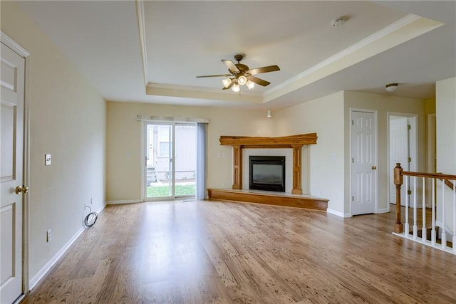 206 SW Chartwell Dr, Lees Summit, MO 64082 - unfurnished living room with a raised ceiling, ornamental molding, a ceiling fan, wood finished floors, and a fireplace