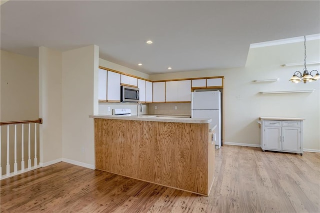 206 SW Chartwell Dr, Lees Summit, MO 64082 - kitchen featuring stainless steel microwave, freestanding refrigerator, light wood-style flooring, light countertops, and a peninsula
