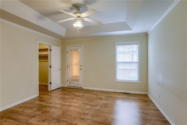 206 SW Chartwell Dr, Lees Summit, MO 64082 - unfurnished bedroom featuring a tray ceiling, ornamental molding, wood finished floors, baseboards, and a spacious closet