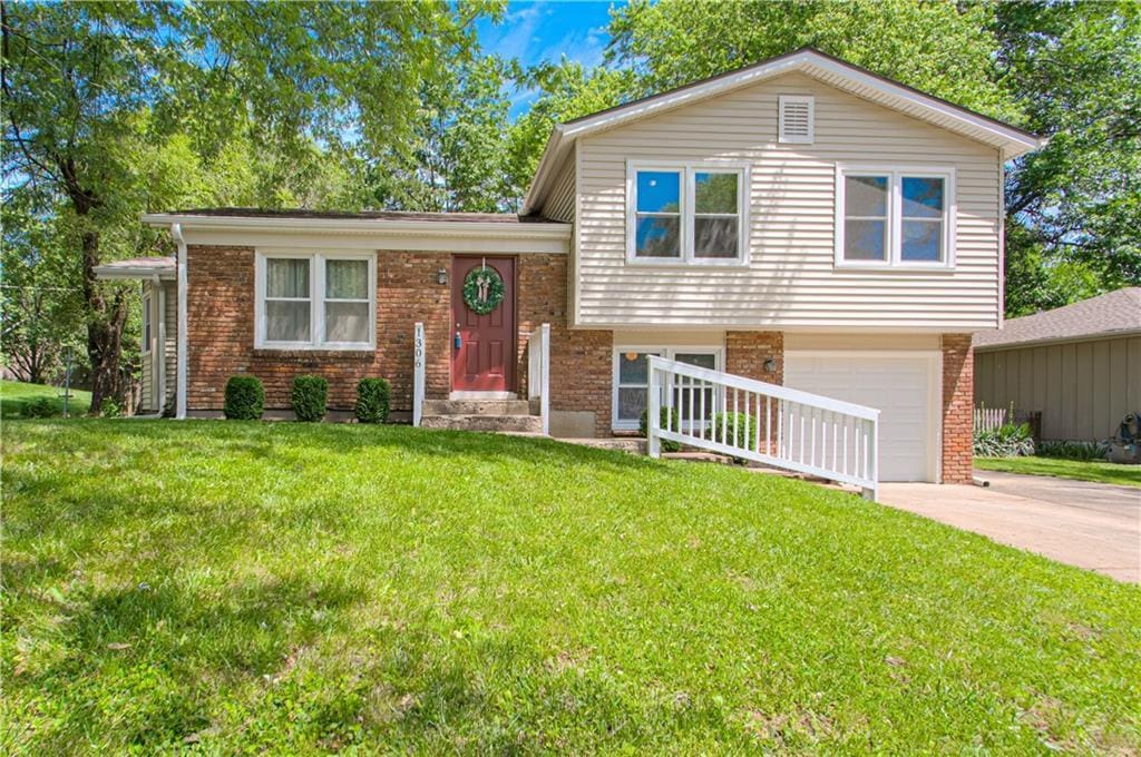 1306 NE 84th Pl, Kansas City, MO 64155 - tri-level home with brick siding, a garage, concrete driveway, and a front yard