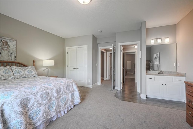 bedroom featuring light colored carpet, a sink, a closet, and baseboards