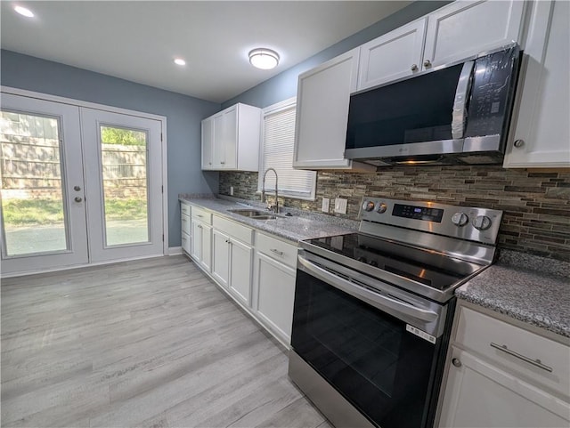 kitchen featuring stainless steel appliances, a sink, decorative backsplash, white cabinetry, and recessed lighting