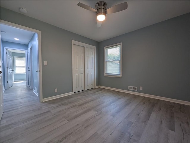 unfurnished bedroom with wood finished floors, baseboards, and multiple windows