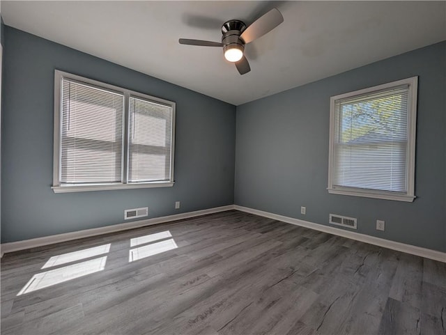 unfurnished room with wood finished floors, a ceiling fan, and baseboards