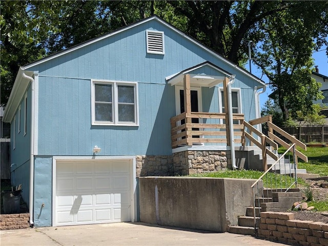 view of front facade featuring an attached garage, stairs, concrete driveway, and fence