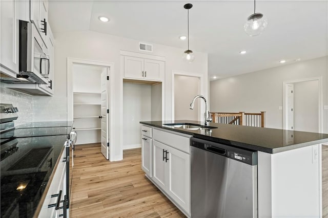 1925 SW Merryman Dr, Lees Summit, MO 64082 - kitchen featuring appliances with stainless steel finishes, a sink, light wood-style floors, backsplash, and white cabinetry