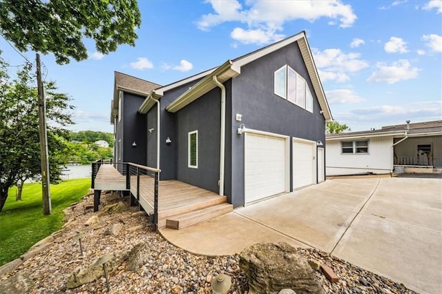 19P Lake Shore Dr, Lake Lotawana, MO 64086 - view of home's exterior with driveway, an attached garage, stucco siding, and a deck