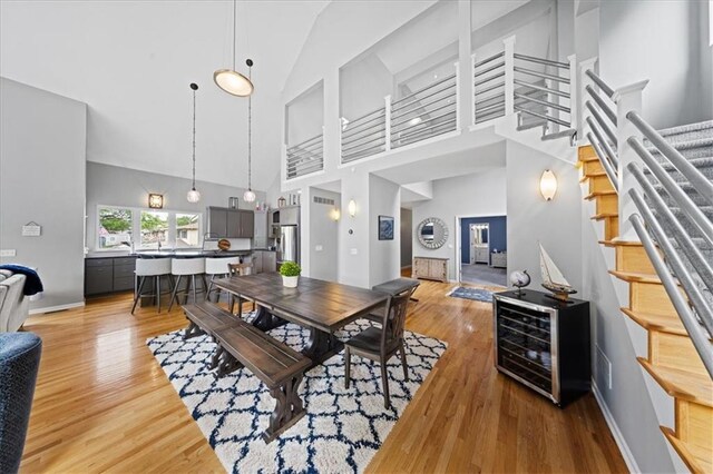 19P Lake Shore Dr, Lake Lotawana, MO 64086 - dining room featuring light wood-style flooring, stairs, high vaulted ceiling, and beverage cooler