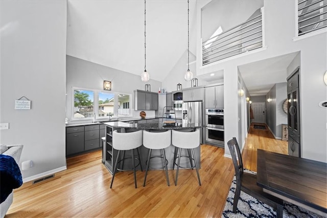 19P Lake Shore Dr, Lake Lotawana, MO 64086 - kitchen featuring high vaulted ceiling, gray cabinetry, a breakfast bar area, light wood-style floors, and stainless steel appliances