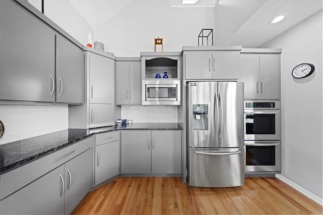 19P Lake Shore Dr, Lake Lotawana, MO 64086 - kitchen with stainless steel appliances, vaulted ceiling, gray cabinets, decorative backsplash, and light wood finished floors