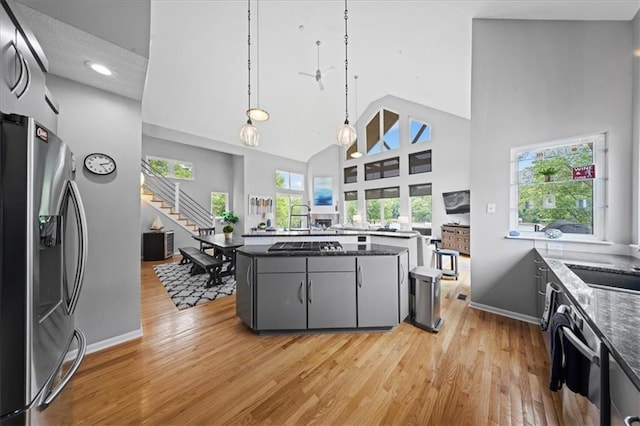 19P Lake Shore Dr, Lake Lotawana, MO 64086 - kitchen featuring appliances with stainless steel finishes, a towering ceiling, light wood finished floors, gray cabinets, and hanging light fixtures