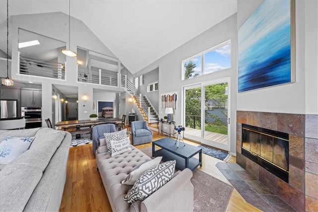 19P Lake Shore Dr, Lake Lotawana, MO 64086 - living area featuring high vaulted ceiling, wood finished floors, a tiled fireplace, and stairway