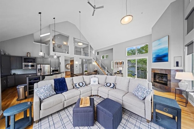 19P Lake Shore Dr, Lake Lotawana, MO 64086 - living area with high vaulted ceiling, a fireplace, stairs, and light wood-style floors