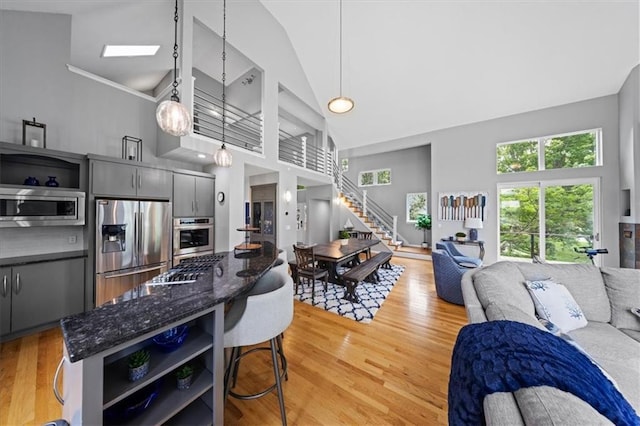 19P Lake Shore Dr, Lake Lotawana, MO 64086 - kitchen featuring stainless steel appliances, open floor plan, open shelves, high vaulted ceiling, and light wood-type flooring