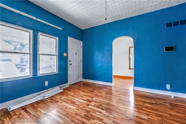 218 S 8th St, Kansas City, KS 66101 - unfurnished room featuring wood finished floors, baseboards, and arched walkways