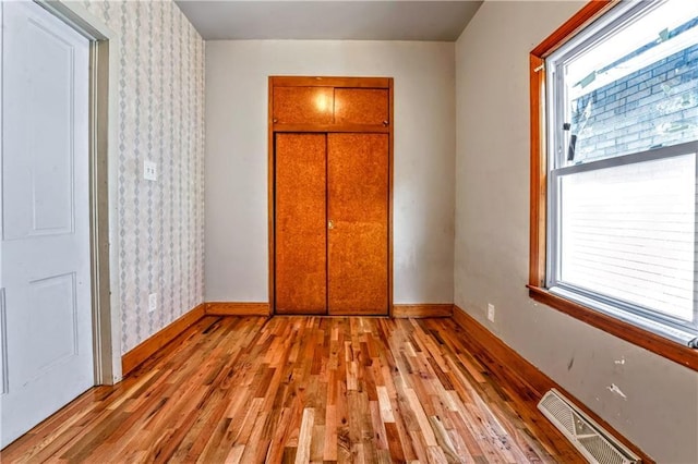218 S 8th St, Kansas City, KS 66101 - unfurnished bedroom featuring wood finished floors, baseboards, and wallpapered walls