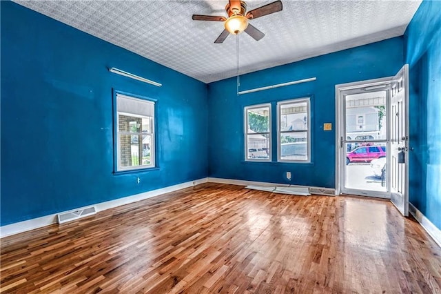 218 S 8th St, Kansas City, KS 66101 - empty room featuring wood finished floors, healthy amount of natural light, a ceiling fan, and baseboards