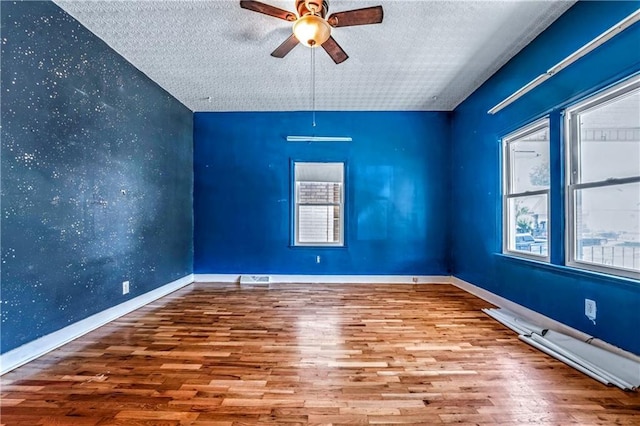 218 S 8th St, Kansas City, KS 66101 - spare room with ceiling fan, wood finished floors, a textured ceiling, an accent wall, and baseboards