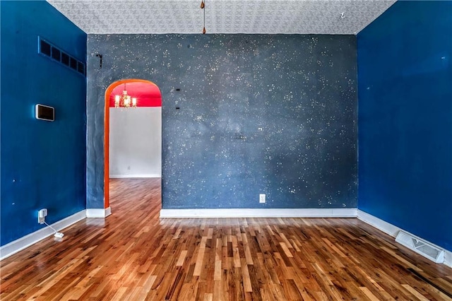 218 S 8th St, Kansas City, KS 66101 - unfurnished room featuring an accent wall, wallpapered walls, wood finished floors, baseboards, and arched walkways