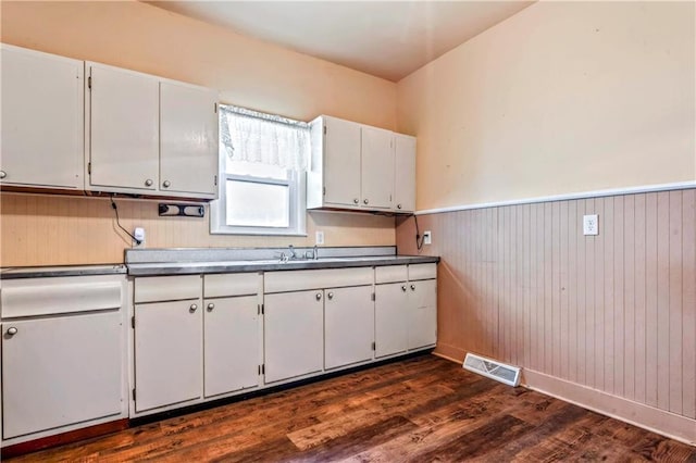 218 S 8th St, Kansas City, KS 66101 - kitchen with white cabinets, dark wood-style flooring, wainscoting, dark countertops, and a sink