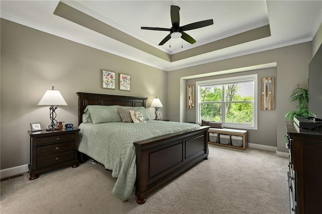 bedroom featuring a raised ceiling, light colored carpet, ornamental molding, baseboards, and ceiling fan