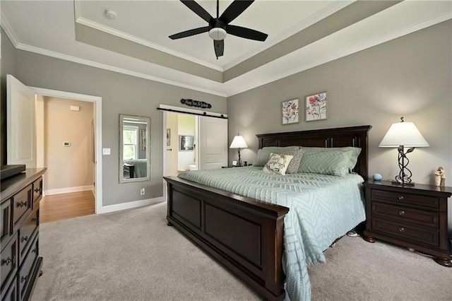 bedroom with light carpet, a raised ceiling, crown molding, baseboards, and a barn door