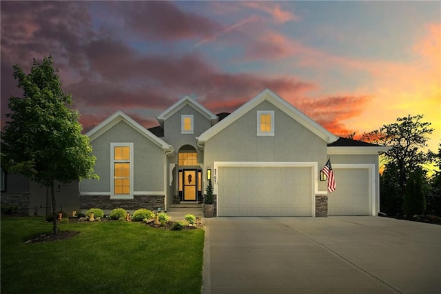 traditional-style home with stone siding, a garage, concrete driveway, and stucco siding