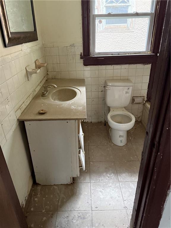 2735 Askew Ave, Kansas City, MO 64128 - bathroom featuring tile walls, tile patterned flooring, vanity, and wainscoting