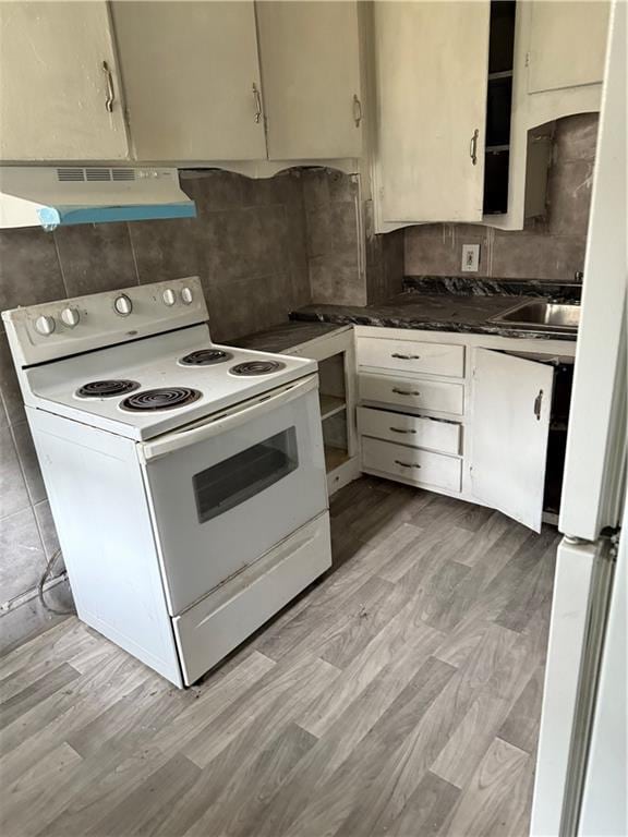 2735 Askew Ave, Kansas City, MO 64128 - kitchen with white appliances, under cabinet range hood, backsplash, and dark countertops