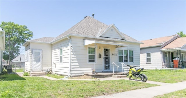view of front of house featuring a front yard and a shingled roof