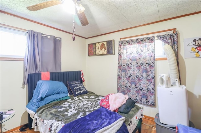 bedroom with ornamental molding, wood finished floors, and a ceiling fan