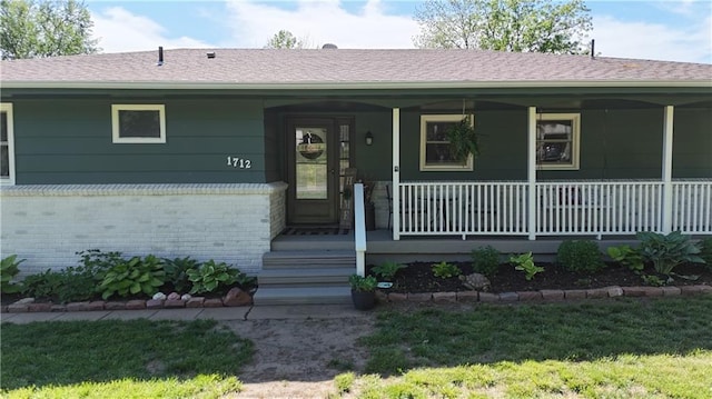 view of exterior entry with covered porch and brick siding
