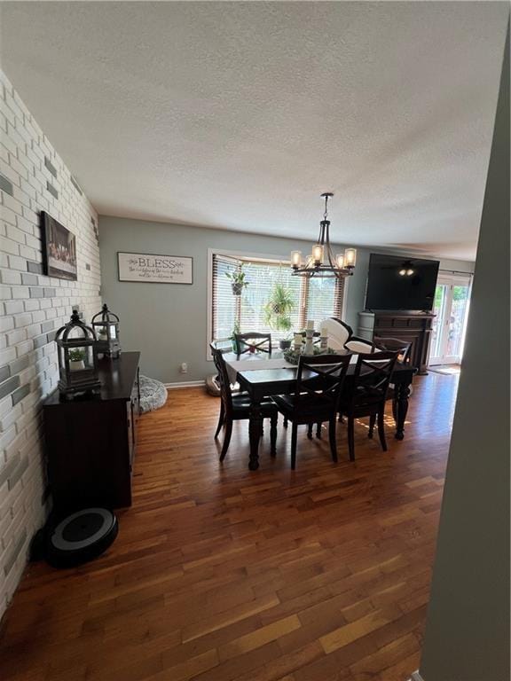 dining room with dark wood-type flooring, a textured ceiling, a chandelier, and baseboards