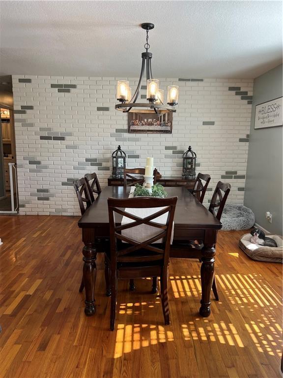 dining space featuring wood finished floors, a textured ceiling, and a chandelier
