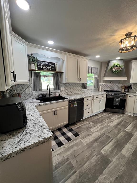 kitchen featuring black dishwasher, range, wall chimney exhaust hood, plenty of natural light, and recessed lighting