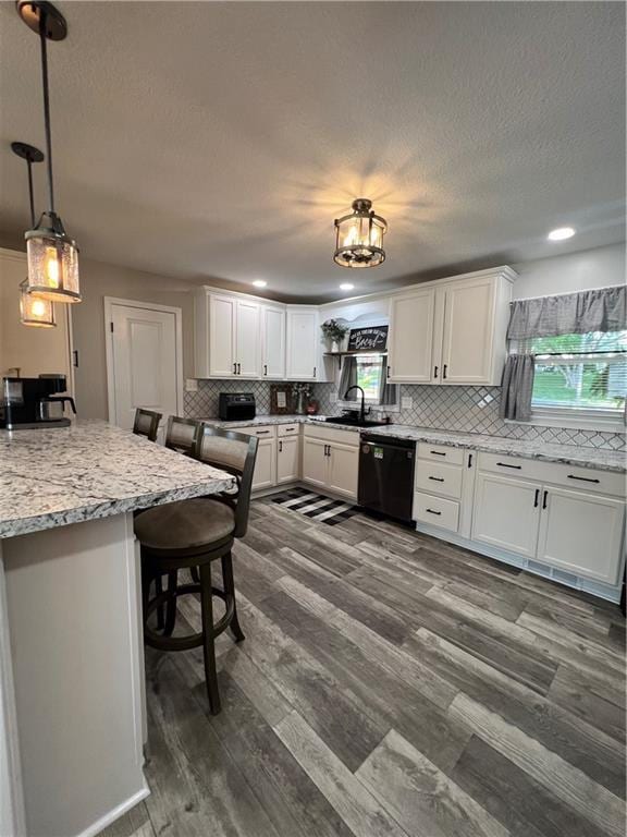 kitchen with dishwasher, a sink, backsplash, white cabinets, and a textured ceiling