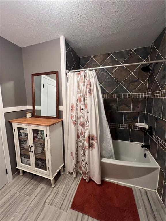 bathroom with a textured ceiling and shower / bath combo with shower curtain