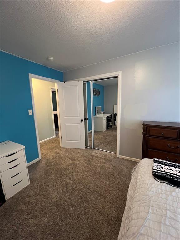 bedroom featuring carpet floors, baseboards, a textured ceiling, and a closet