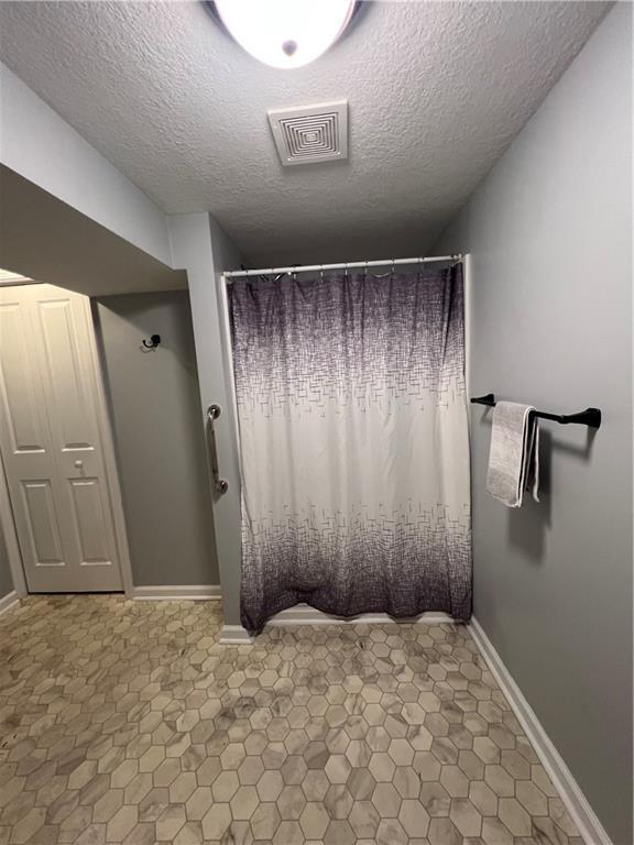 bathroom featuring a textured ceiling and a shower with curtain
