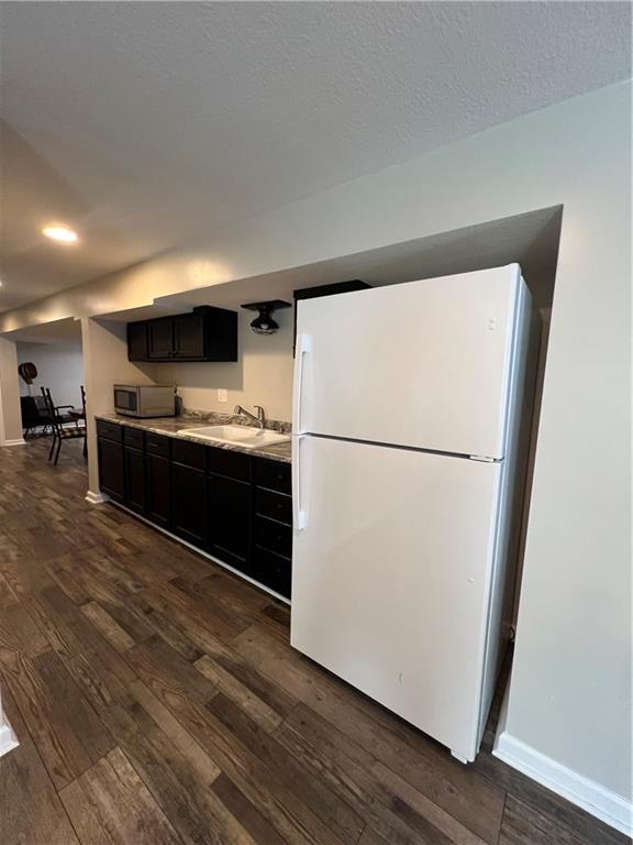 kitchen featuring freestanding refrigerator, stainless steel microwave, dark wood finished floors, and recessed lighting