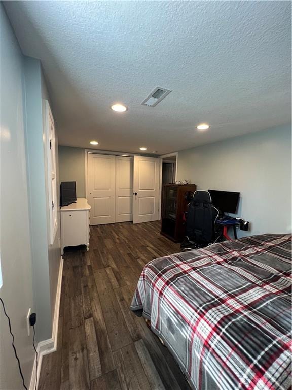 bedroom with dark wood-type flooring, recessed lighting, a textured ceiling, and a closet