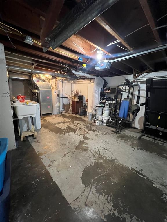 unfinished below grade area featuring electric water heater and a sink