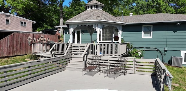 view of front of property with a wooden deck, roof with shingles, central AC unit, and a gazebo