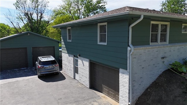 view of side of property with brick siding, a garage, and an outdoor structure