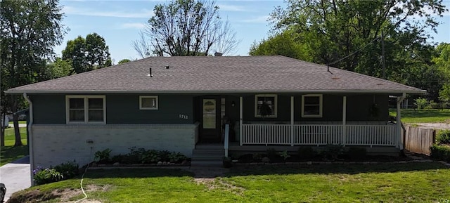 view of front of house featuring a front yard, covered porch, brick siding, and a shingled roof