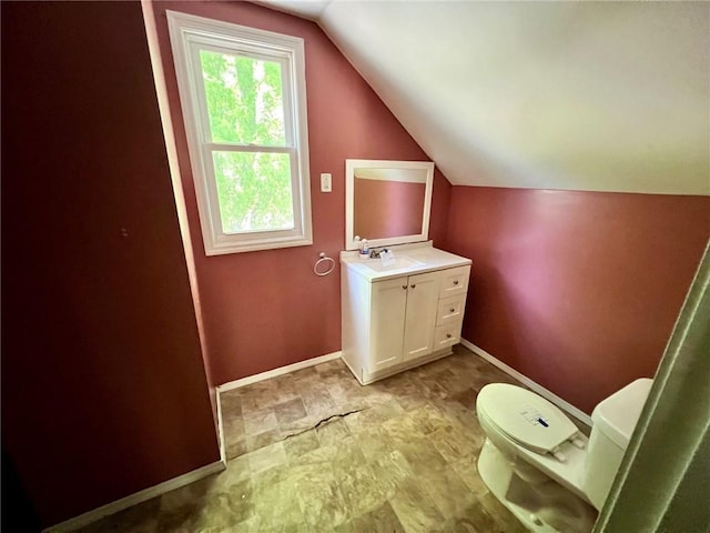 bathroom featuring lofted ceiling, toilet, baseboards, and vanity